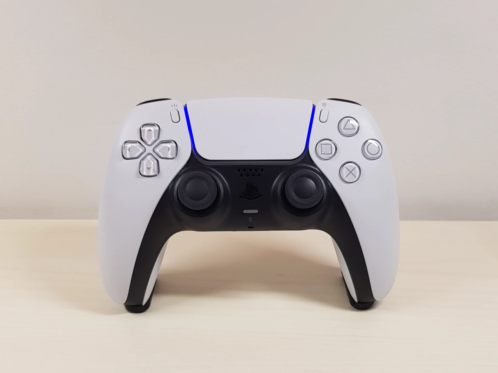Controle branco e preto de frente apoiado no suporte preto sobre a mesa